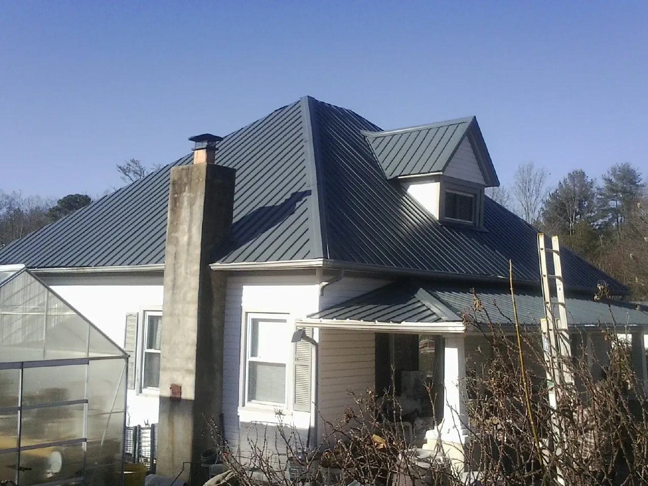 Dark blue standing seam metal roof on a white farmhouse with dormer — Slate & Tile Roof Repair by Roofing Brothers in Summer Shade