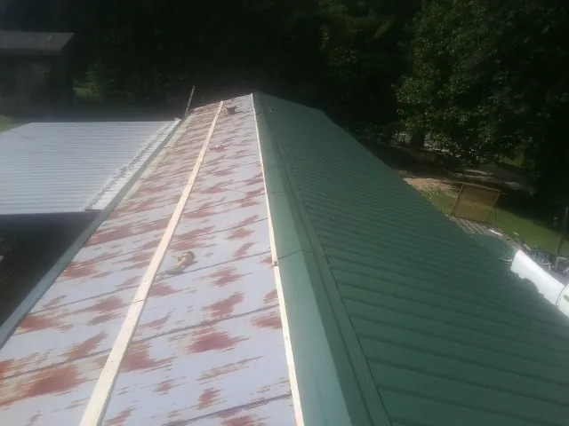 Old rusted panels beside newly installed green metal roofing — Wind Damage Roof Repair by Roofing Brothers in Summer Shade