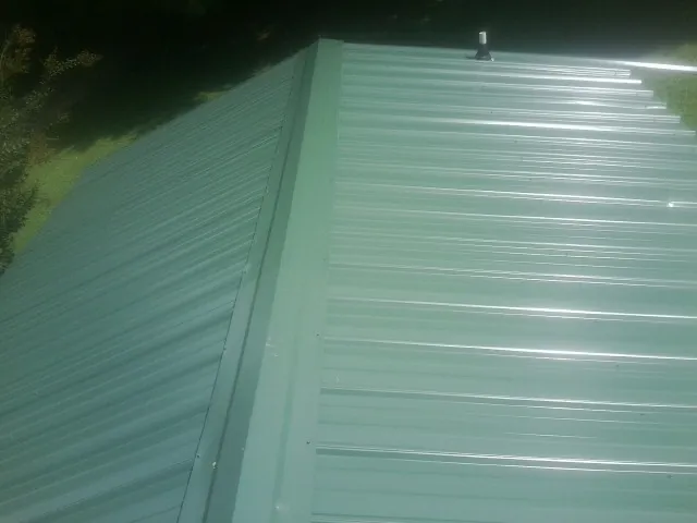 New green metal panels meeting at the ridge of a roof — Flat Roof Repair work by our crew in Summer Shade