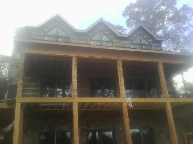 Dormers and porch framing on a large log home under construction — Roof Coating work by our crew in Summer Shade