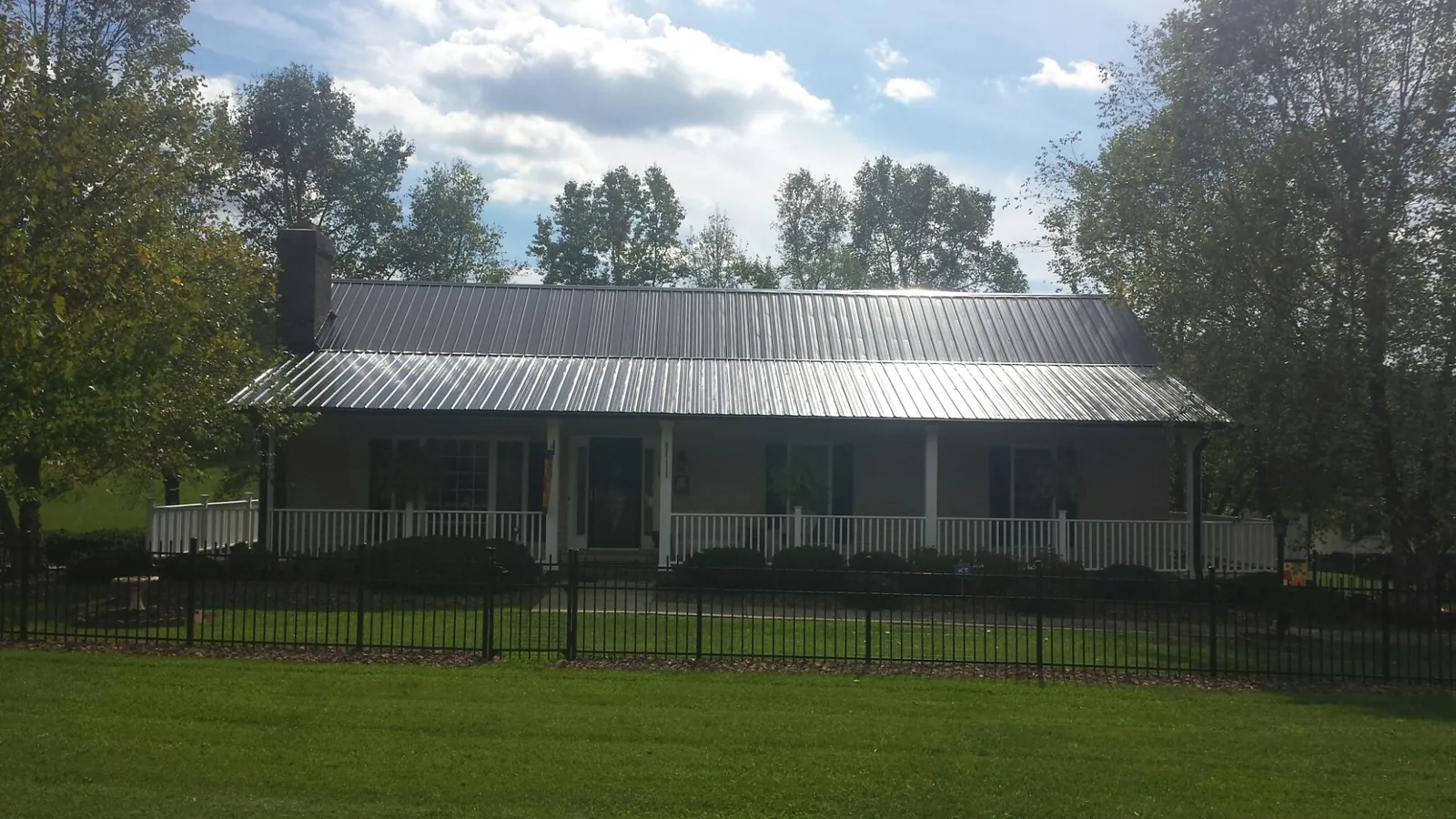 Gray metal roof on a brick ranch with a full width front porch — Gutter Guard Installation work by our crew in Summer Shade