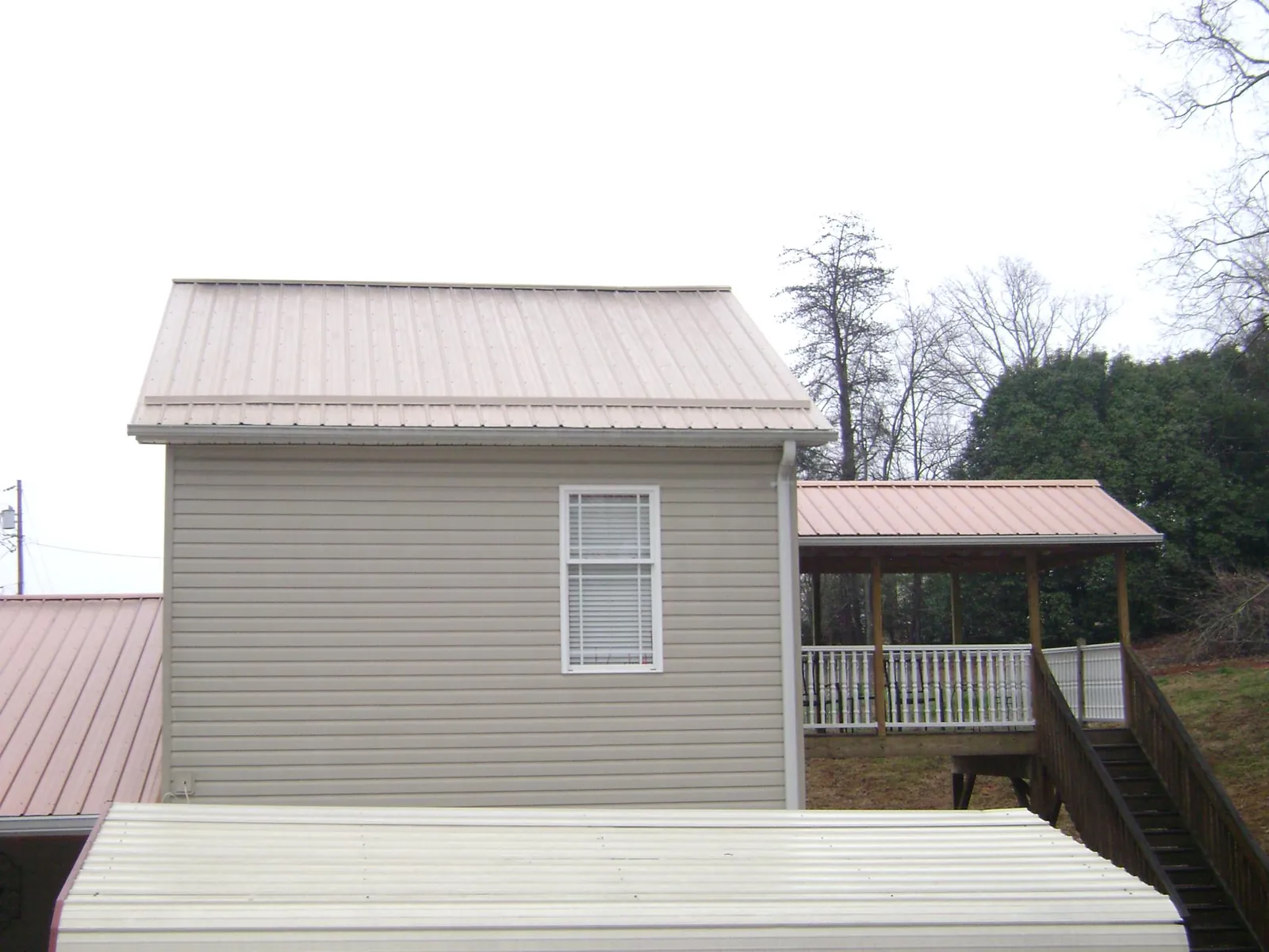 Tan metal roofs on a two story addition and attached porch, from a Roof Replacement job in Summer Shade