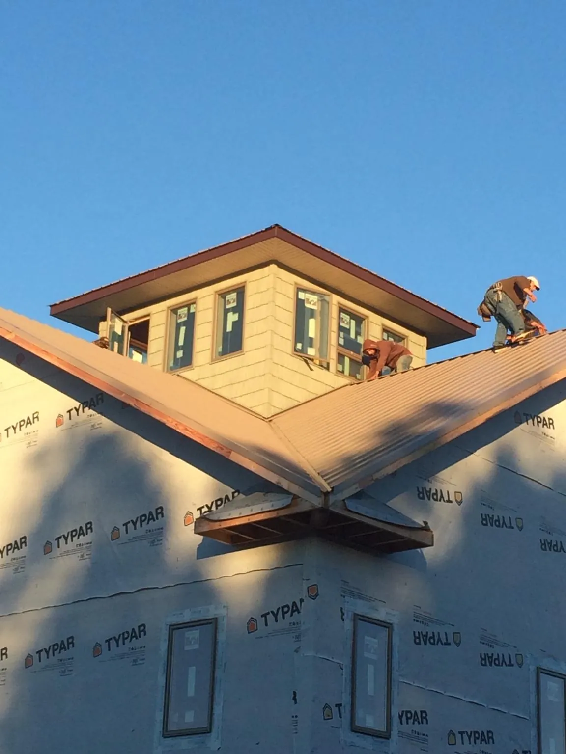 Roofers working around a rooftop cupola on a new metal roof at sunset — Roof Waterproofing in Summer Shade by Roofing Brothers